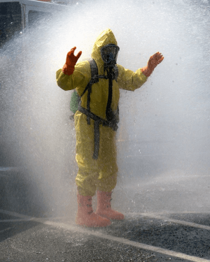 Fire fighter in hazmat suit getting sprayed down