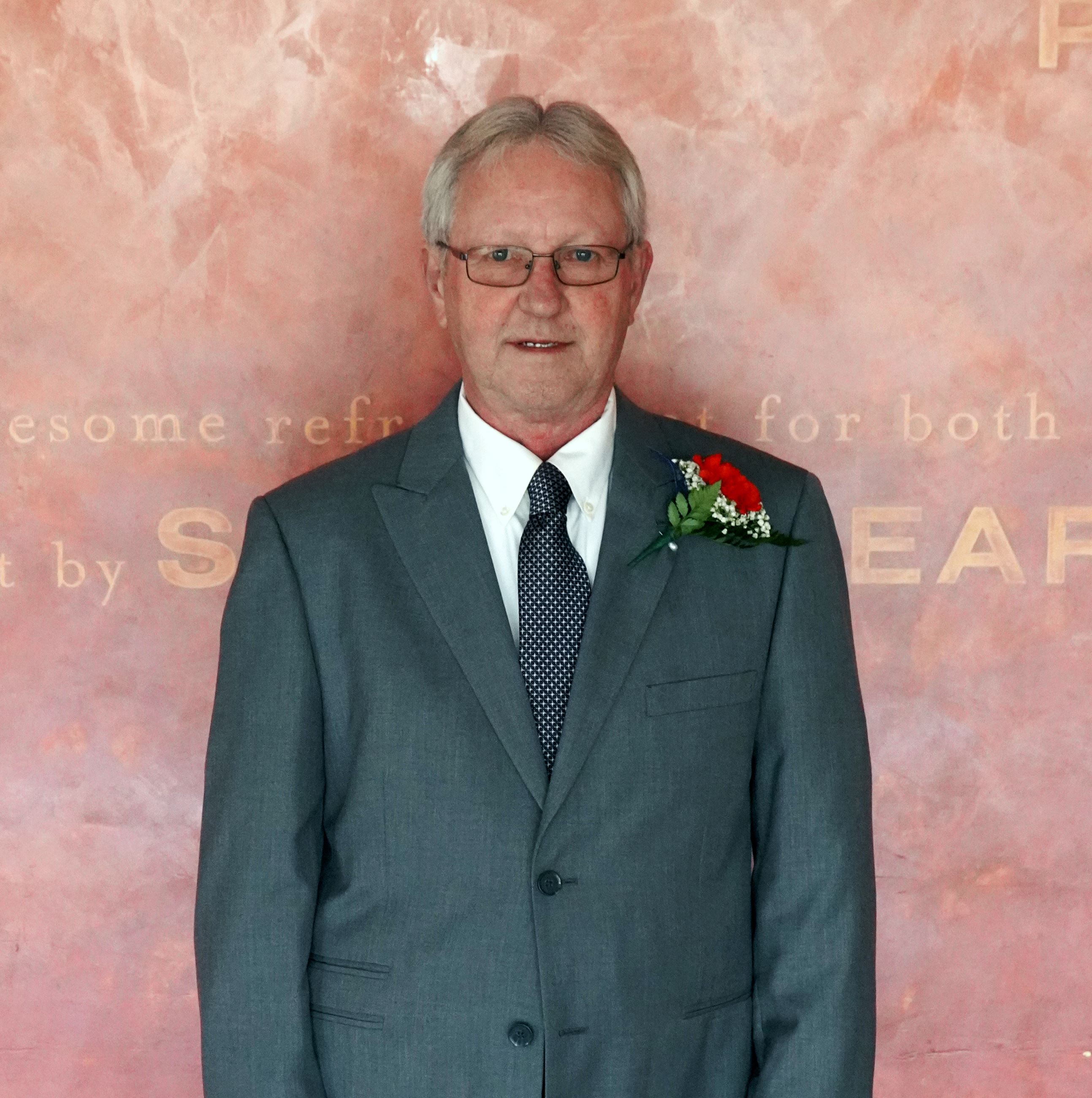 Shorter white male with glasses smiling in gray suite