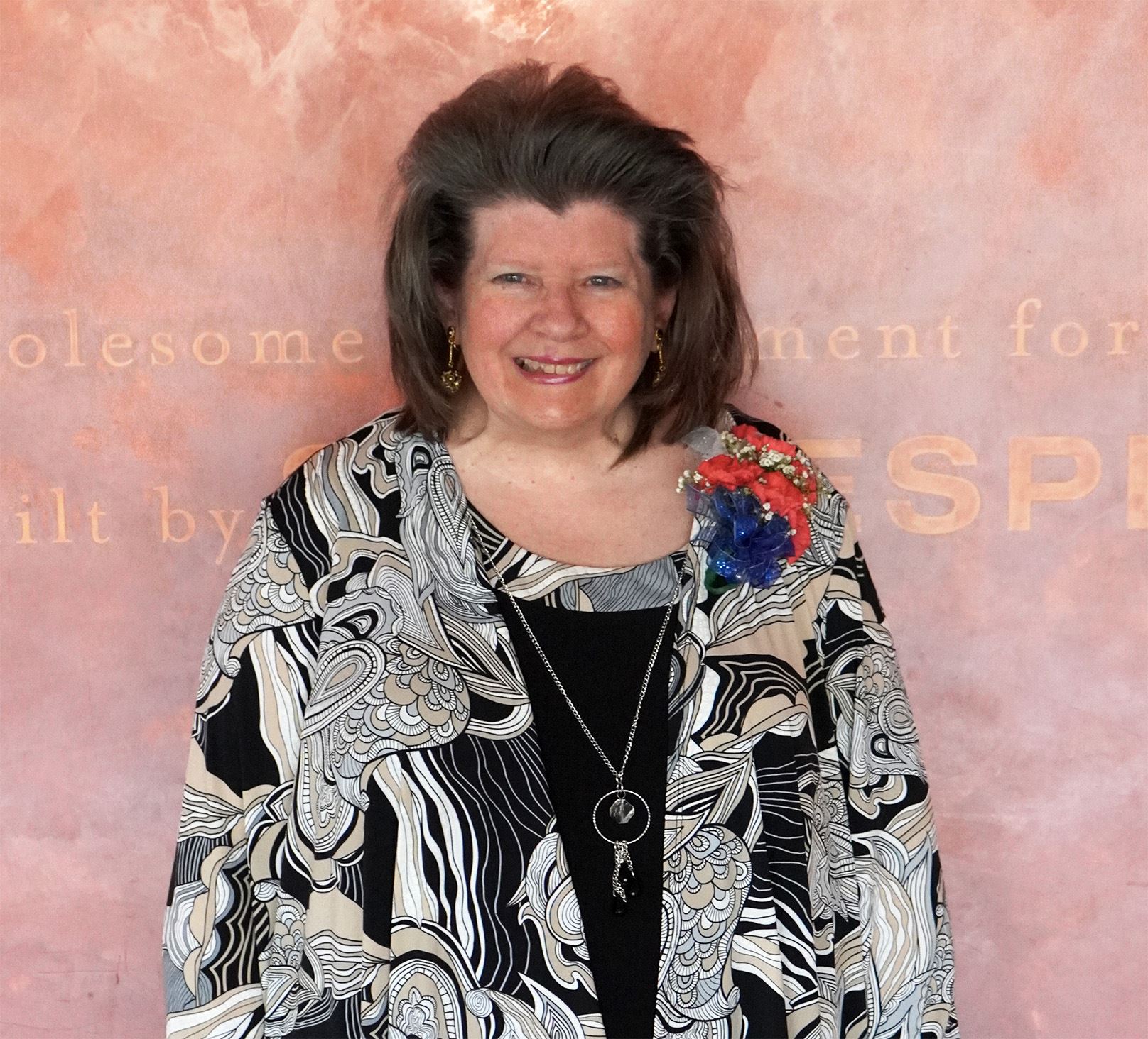 Short white female with brown hair wearing floral top smiling
